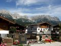 Ellmau in Tirol - der Kirchhof der Pfarrkirche zum Hl. Michael vor alpenländischen Häusern mit dem Wilden Kaiser im Hintergrund