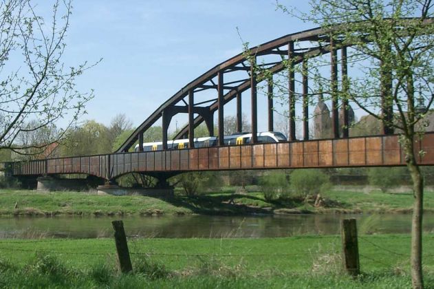 Die Eisenbahnbrücke über die Weser bei Corvey, im Hintergrund das karolingische Westwerk Die Eisenbahnbrücke über die Weser bei Corvey, im Hintergrund das karolingische Westwerk